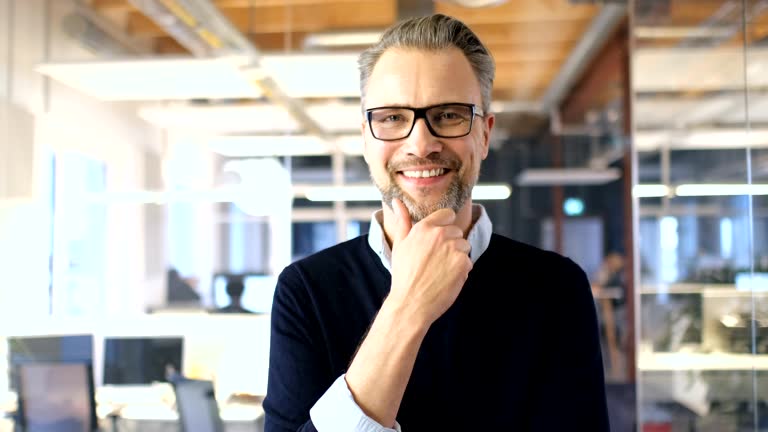 Smiling businessman with hand on chin in office