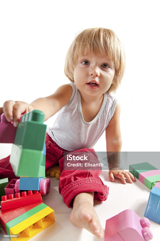 Cute little boy playing with blocks Cute little boy playing with blocks and stretching one in camera  18-23 Months Stock Photo