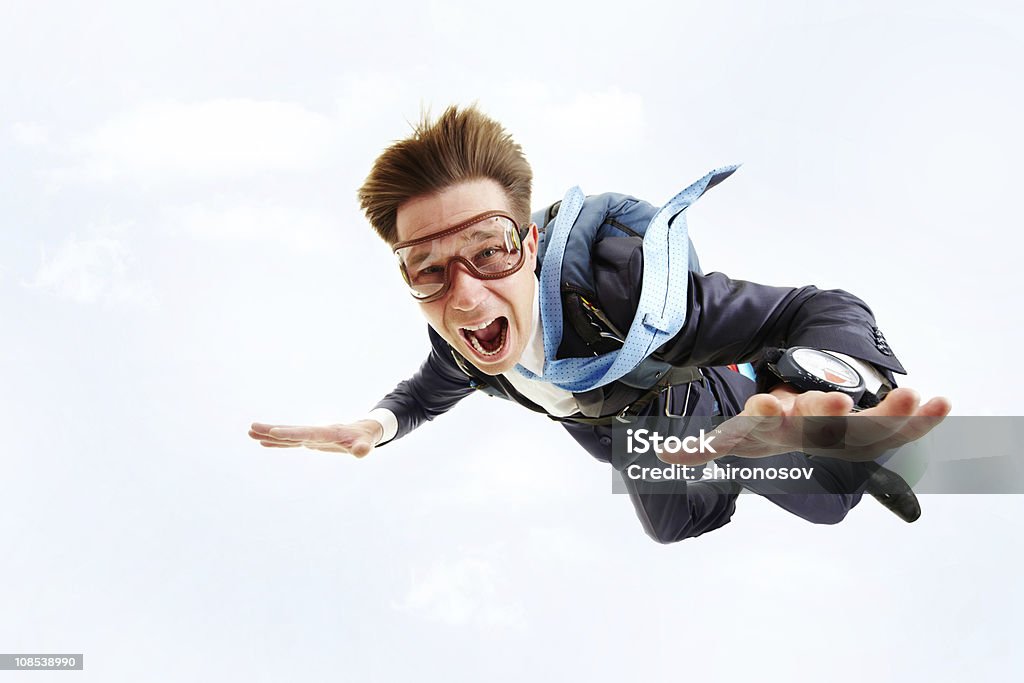 A man in a blue suit and goggles parachuting Conceptual image of young businessman flying with parachute on back Fear Stock Photo