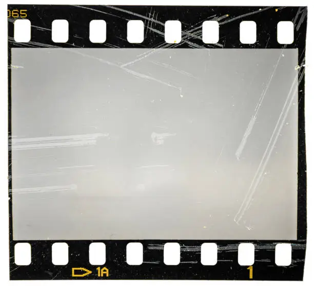 Photo of scratched 35mm filmstrip or film frame on white, old retro vintage film material, macro photo