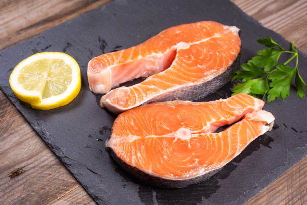 istock Two fresh raw salmon steaks with lemon and parsley on rustic table 1085400282
