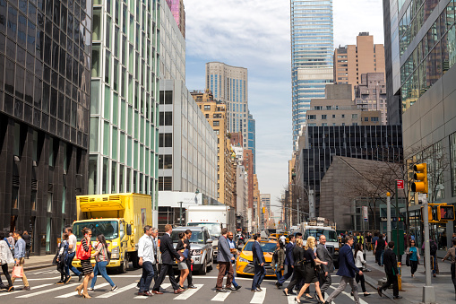 Street scene in Midtown Manhattan with pedestrians crossing Park Avenue at the intersection,  cars standing at traffic light.