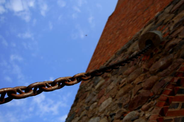 Chain rings suspended between brick red wall and clear sky , Vilnius