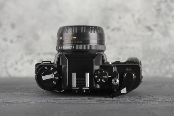 Old 35 mm SLR camera on a gray cement background.