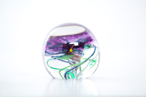 A glass ball with multi colored swirls inside.