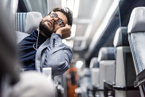 Tired young businessman sleeping while traveling by train.