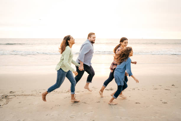 istock Two parents and two kids running on the beach 1085472170