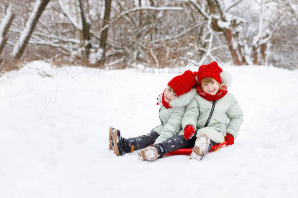 istock Children twins are sitting on the snowy ground. 1085474844