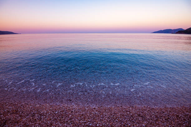 Long wave on the coast, dawn on the sea, Turkey large foam waves in the sand, diagonal clouds, yellow light of dawn in the blue sky