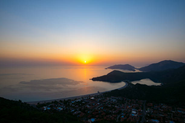 Panoramic view of rocky shores covered with lush pines, surrounded by turquoise waters of the Mediterranean Sea during sunset - Oludeniz, a tourist landmark in Turkey. Wide angle.