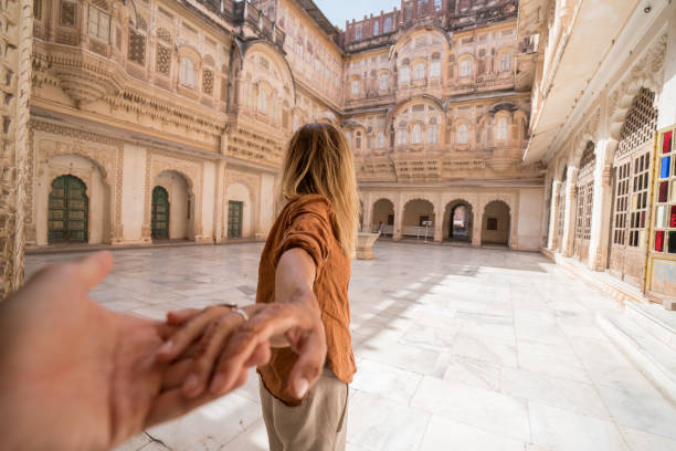 suivez-moi au concept ; femme conduisant des mains de tenue de petit ami à l’intérieur du fort au coucher du soleil en inde - mehrangarh photos et images de collection