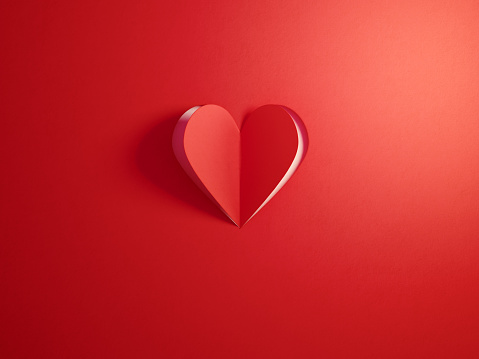 Red cut out heart shape folding on white background. Horizontal composition with  copy space.