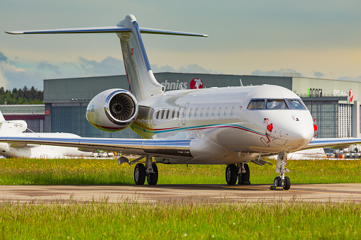 Kloten, Switzerland - May 4, 2015: a Bombardier Global 5000 airplane at Zurich airport, summits of the Alps in the background. The Bombardier Global Express is a large cabin, ultra long range business jet manufactured by the Bombardier Aerospace company in Toronto, Ontario, Canada. Zurich Airport is the largest airport in Switzerland.