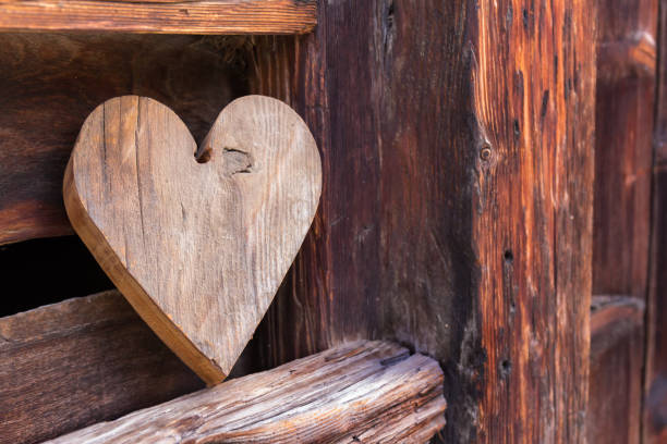 coeur en bois à l’extérieur d’une grange rustique en signe de bienvenue - barn red old door photos et images de collection