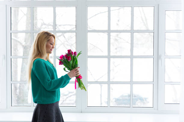 istock young beautiful woman with tulips by the window, 8 March, copyspace. 1085545032