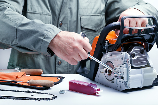 Repair of chainsaws, gasoline powered tools. Man repairing chainsaw.