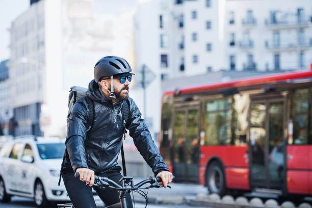 Male courier with bicycle delivering packages in city. Copy space. Male hipster courier with bicycle cycling on a busy road in city, delivering packages. Copy space. energy fuel and power generation city urban scene stock pictures, royalty-free photos & images