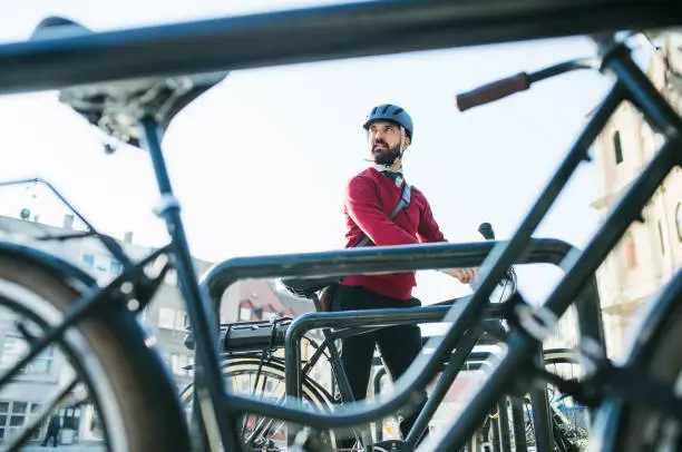 Photo of Hipster businessman commuter parking electric bicycle in city when going to work.