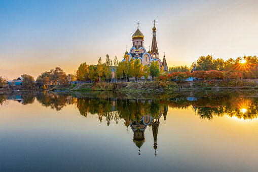 Iglesia ortodoxa de Rusia conocida como iglesia de la exaltación de la Santa Cruz y su reflexión, en la puesta del sol, en Almaty, Kazajstán photo