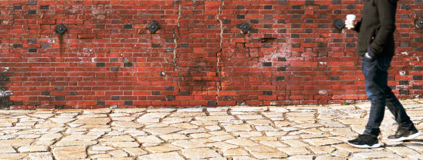 istock blurred man walking through a old weathered brick wall hold coffee cup 1085625068