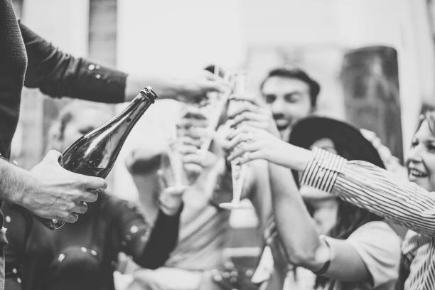 wielorasowa grupa młodych przyjaciół bawiących się pijąc i opiekając kieliszki szampana na schodach uniwersyteckich - szczęśliwi ludzie świętują ukończenie studiów z butelką prosecco w mieście na świeżym powietrzu - champagne celebration glass black zdjęcia i obrazy z banku zdjęć