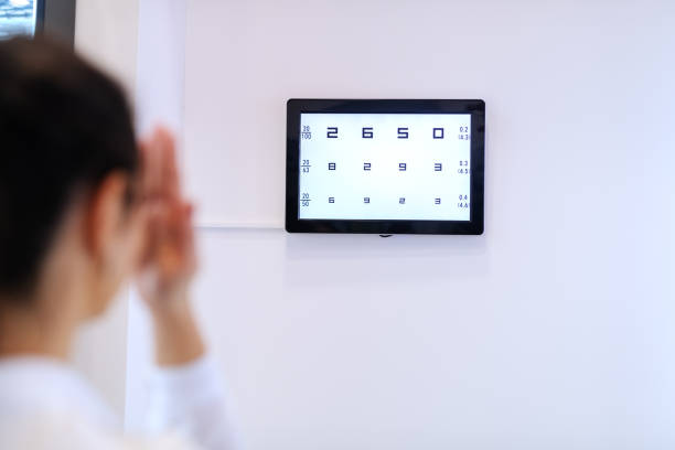 Woman checking her sight while looking at numbers on the wall at the optician.