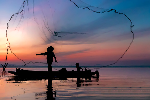 Image is silhouette. Fishermen Casting are going out to fish early in the morning with wooden boats, old lanterns and nets. Concept Fisherman's life style.