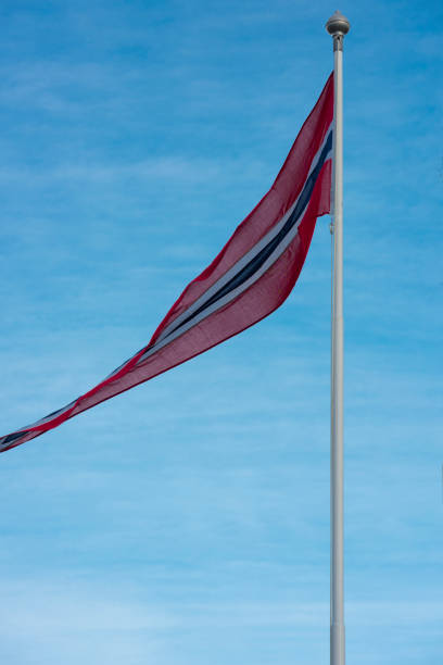 Pennon or pennant of the Kingdom of Norway in red, white and blue against blue sky on windy day in winter.