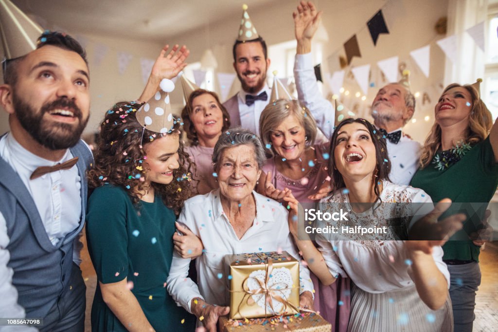 A portrait of multigeneration family with presents on a indoor birthday party. A portrait of multigeneration family with presents standing indoor on a birthday party. Party - Social Event Stock Photo