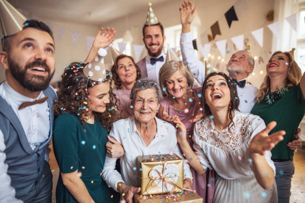 A portrait of multigeneration family with presents on a indoor birthday party. A portrait of multigeneration family with presents standing indoor on a birthday party. headwear photos stock pictures, royalty-free photos & images