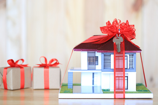 Real estate and Gift new home concept,Model house with Red ribbon and key on wooder background