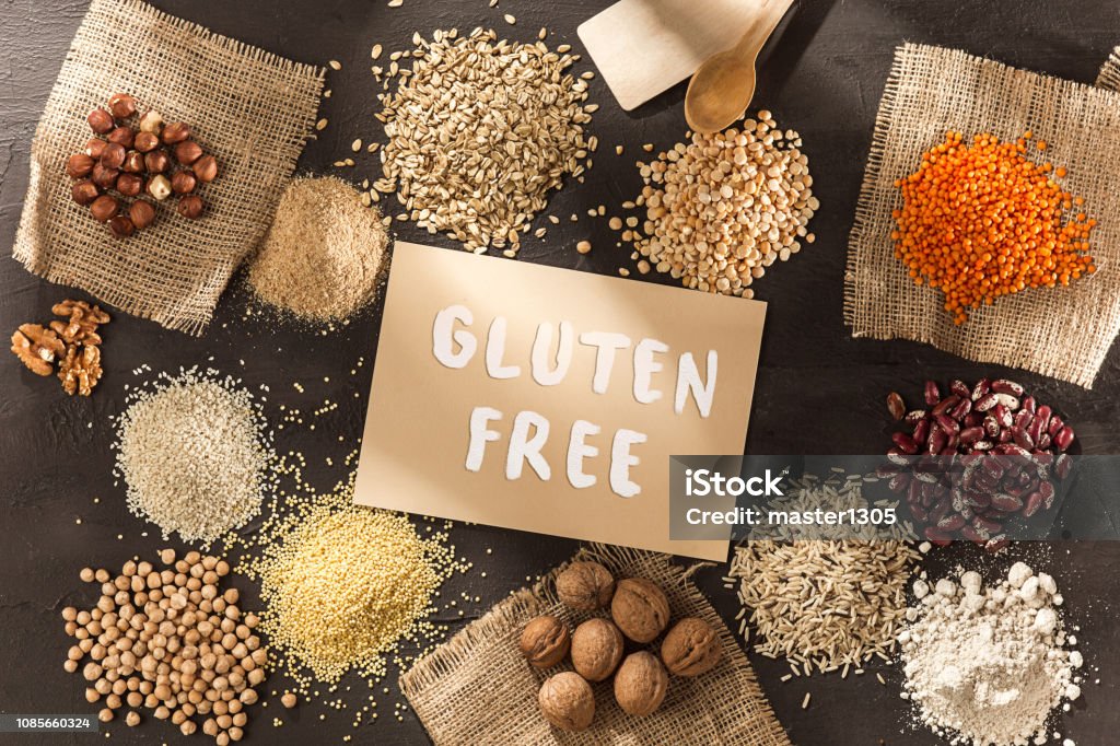 Gluten free flour and cereals millet, quinoa, corn bread, brown buckwheat, rice with text gluten free Gluten free flour and cereals millet, quinoa, corn bread, brown buckwheat, rice, bread and pasta with text gluten free in English language with spoon on wooden background, top view Dough Stock Photo