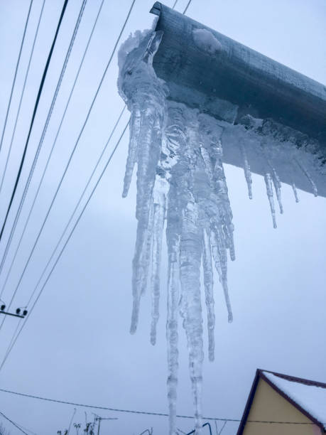 istock Icicles on the drainpipe and ditch. Incorrect installation of the drainage system, on which large icicles appear that pose a threat to the health and lives of people passing by. 1085673162