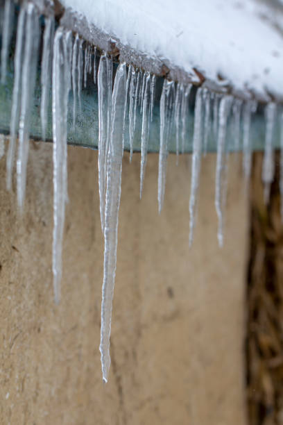 istock Icicles on an old, rusty, rural roof. Clay wall 1085673170