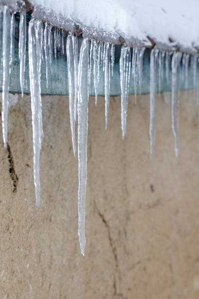 istock Icicles on an old, rusty, rural roof. Clay wall 1085673184