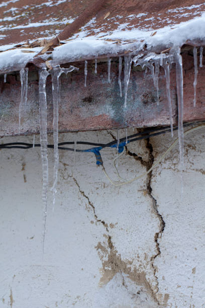 istock Icicles on an old, rusty, rural roof. Clay wall 1085673186