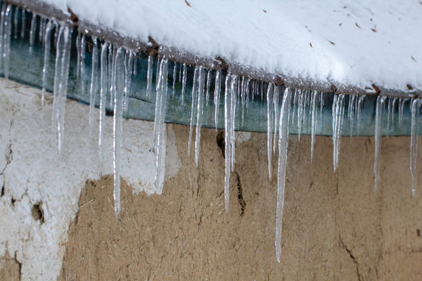 istock Icicles on an old, rusty, rural roof. Clay wall 1085673192