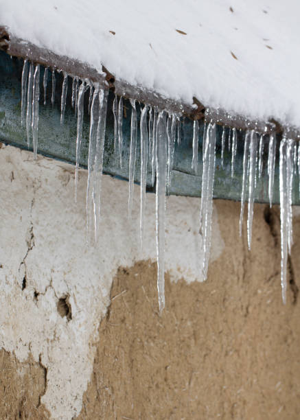 istock Icicles on an old, rusty, rural roof. Clay wall 1085673196