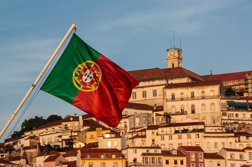 A Portuguese flag with the city of Coimbra behind.