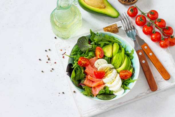 diät-menü, veganes essen. gesunder salat mit rucola, tomaten, lachs, ei und avocado auf einem weißen stein tisch. kopieren sie raum. - 16286 stock-fotos und bilder