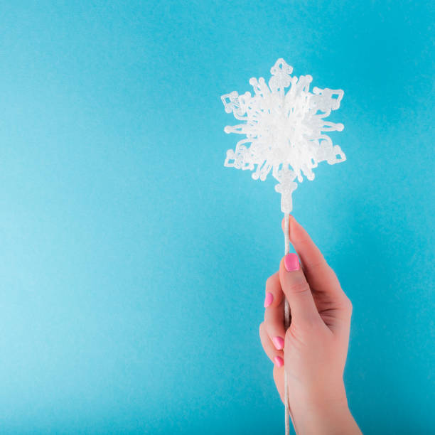 istock Female hand holding decorative white snowflake on a stick 1085689504