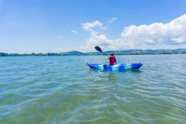 istock Young boy paddling blue and white kayak in harbor. 1085699192