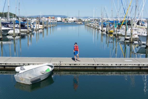 marina mit festgemachten boote in ruhigen blauen wasser und kleiner junge - water reflection marina life jacket stock-fotos und bilder