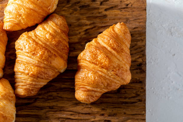 istock Butter croissants on a rustic wooden board. Aerial view on light background. 1085699680