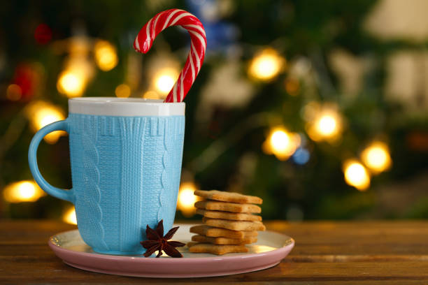 blue mug with Christmas candy and gingerbread cookies on the background of Christmas lights