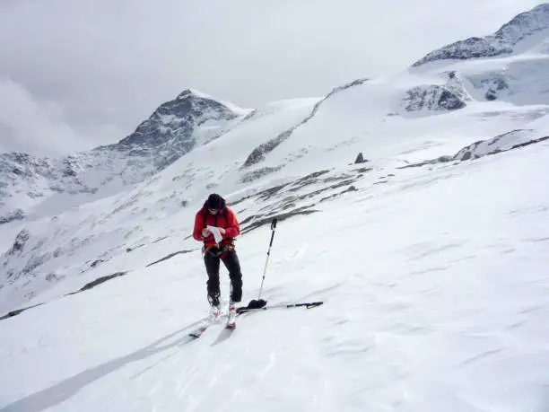 backcountry skier mountain guide looking at a map in the high alpine mountains of Austria in the Hohen Tauern region while guiding a group of clients