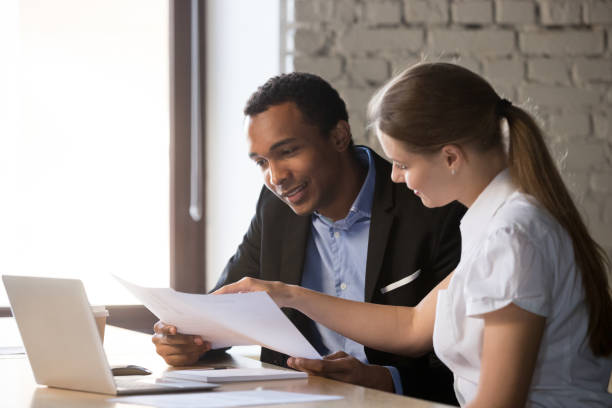 Female financial advisor insurer consulting male african-american client about contract Female financial advisor insurer banker consulting male african american client about contract, caucasian mentor hr and black intern new employee discussing documents at meeting advice brokers stock pictures, royalty-free photos & images