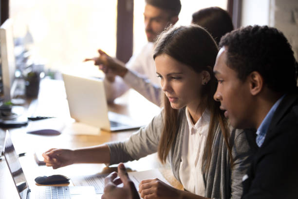 istock Diverse millennial employees working together using laptop in office 1085713924