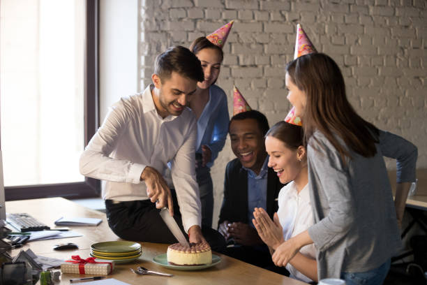 Friendly multi-ethnic employees cutting cake celebrating birthday together