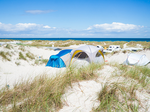 Camping tent on a grass field with a sea in the background